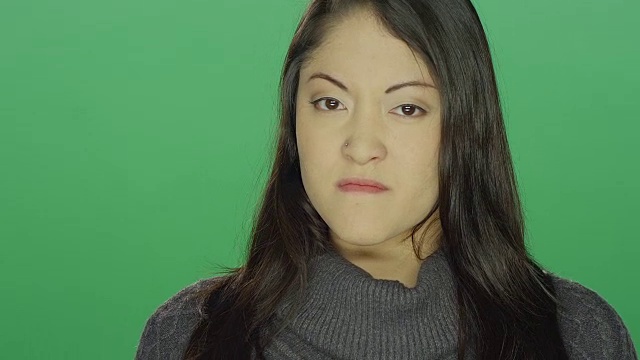 美丽的年轻亚洲女人看起来恼怒和生气，在一个绿色屏幕的工作室背景视频素材