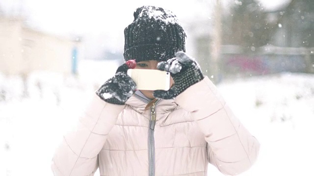 女人在冬天用智能手机拍照视频下载