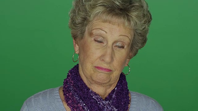 一个年长的女人看起来很失望，在一个绿色屏幕的工作室背景视频素材