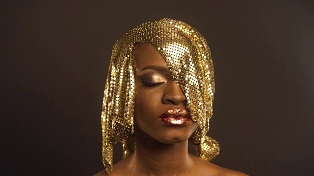 时尚肖像光泽非洲裔美国妇女与明亮的金色化妆。青铜身体油漆，黑色工作室背景视频下载