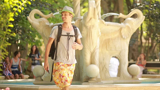 帅哥游客在喷泉边打电话。亚洲之旅视频下载