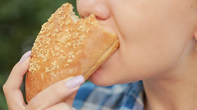 年轻女孩在吃三明治。快餐的概念。三明治咬视频下载