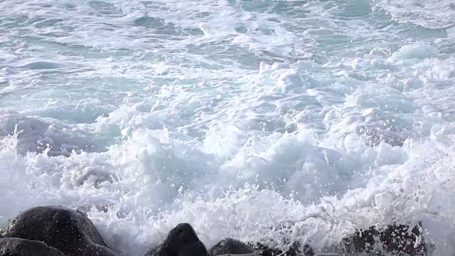 慢镜头特写:白色的海浪撞击和溅溅在火山岩上视频素材