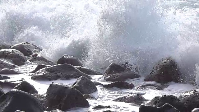 慢镜头特写:海浪撞击和溅溅圆形的火山岩视频素材