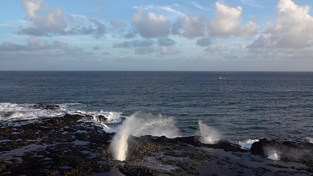 慢动作:巨大的海浪从火山海岸的岩石气孔上升视频素材