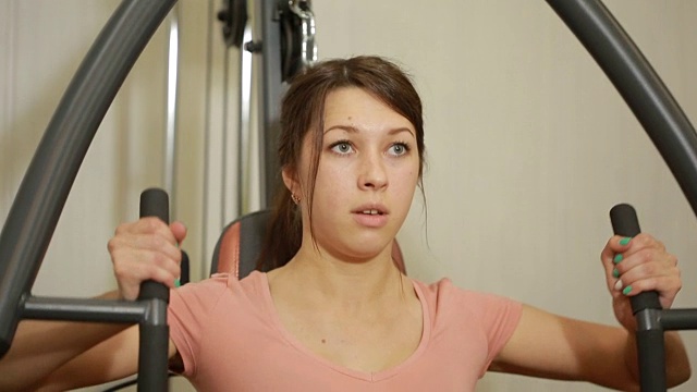 美丽的女孩在健身房训练。女人从事运动模拟器视频下载