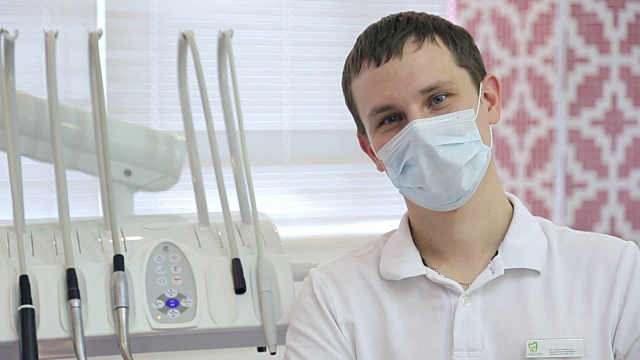 年轻的牙科专业人员坐在牙科单位旁边的口罩视频素材