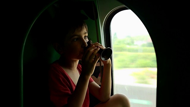 孩子在公共交通工具上玩玩具喇叭。小男孩乘火车旅行时感到无聊视频下载