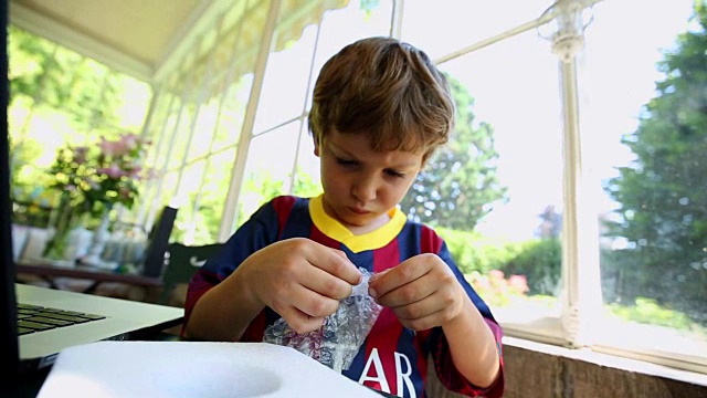 孩子在玩泡沫包装。小男孩捏着泡泡纸。孩子们的泡泡纸视频下载