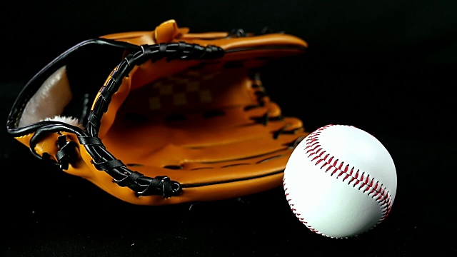 黑色背景下的棒球手套和球，慢动作视频下载