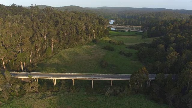 航拍:飞过横跨广阔的绿色沼泽景观的桥梁公路视频素材