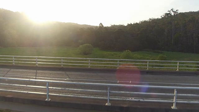 空中特写:一辆白色越野车开过绿色沼泽上的桥视频素材