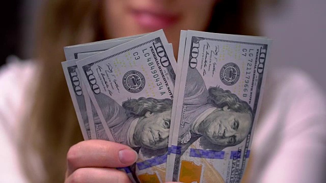 一个女人数着100美元的钞票视频素材