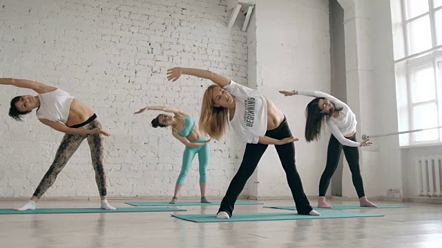 年轻女孩做瑜伽，一群人在伸展课上，健康的生活方式视频下载
