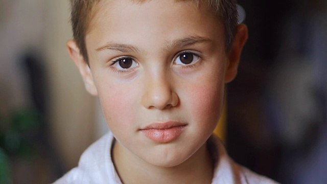 一个可爱的小男孩的肖像，大眼睛看着相机视频下载