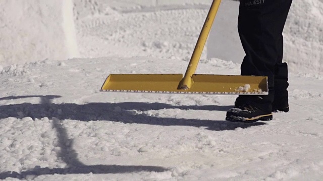 在滑雪胜地，人们用铁锹清除斜坡上的雪。阳光明媚的一天。喷洒。雪堆视频下载