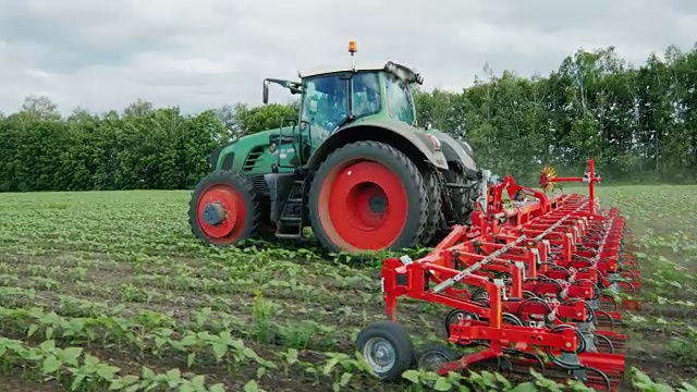 斯坦尼康镜头:拖拉机拉在田里的中耕机:这削减杂草视频下载