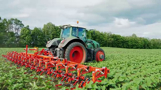斯坦尼康飞周围拍摄:拖拉机拉的田地，农业机械除草植物视频下载