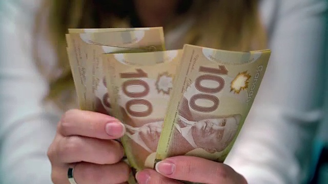 一个女人数着加拿大的100美元视频素材