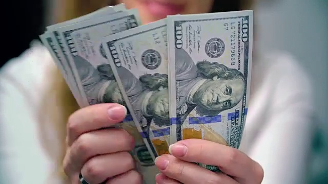 一个女人数着100美元的钞票视频素材