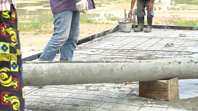 建筑工人从水泥搅拌机中倒入混凝土混合物。视频素材