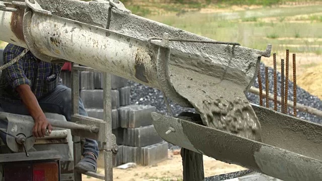 建筑工人从水泥搅拌机中倒入混凝土混合物。视频素材
