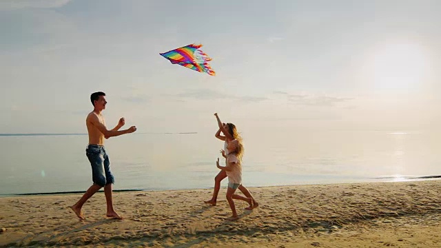 两姐妹跑向正在放风筝的哥哥。家庭幸福，童年无忧无虑视频素材
