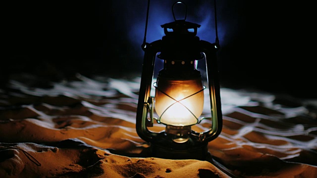 古老的油灯站在沙滩上，在黑暗中闪闪发光视频素材