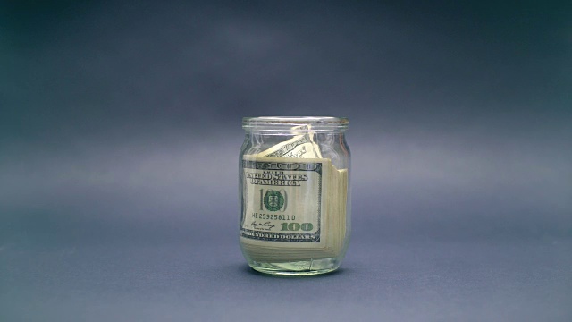 女人把100美元放进一个玻璃罐里视频下载