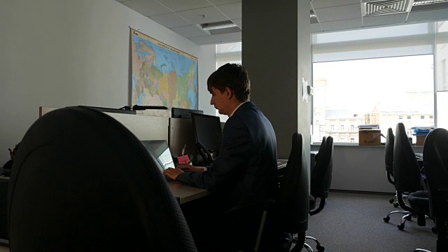 一个年轻的白人在空荡荡的办公室里用笔记本电脑工作。多莉拍摄视频下载