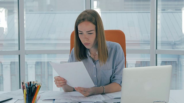年轻漂亮的女人忙着处理电脑，办公室里的文件视频素材