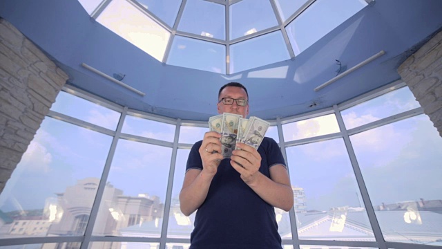 男人在明亮的全景窗口数美元。省钱、经济、现金的概念视频下载