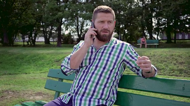 在公园长椅上用智能手机聊天的男人。替身。视频素材