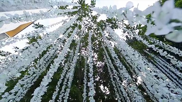 白色花朵装饰的吊灯在婚礼的花园里摇曳。视频素材
