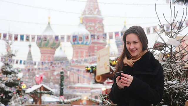 冬天里，在莫斯科的红场上，一名女子站在圣巴西尔大教堂前打电话视频下载