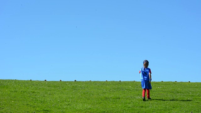 超级英雄小女孩在绿色的田野里奔跑视频素材