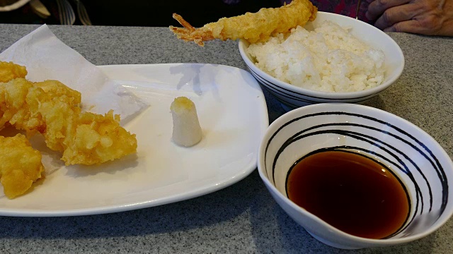 妇女用筷子用手吃炸虾——天妇罗日本菜视频素材