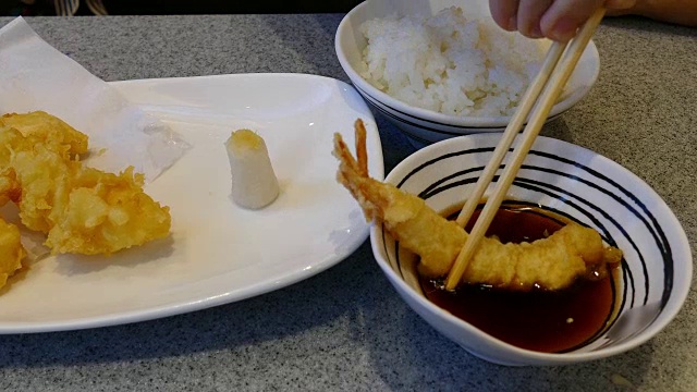 妇女用筷子用手吃炸虾——天妇罗日本菜视频下载