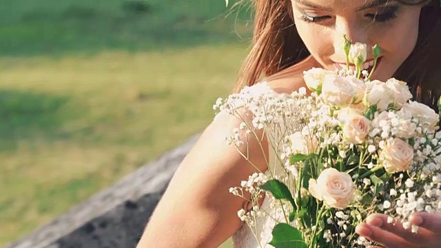 新娘闻着花束，微笑着看着太阳。慢慢地视频素材
