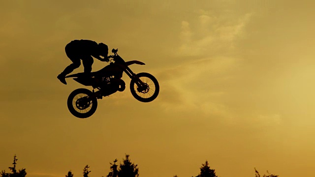 慢动作:极限专业摩托车越野赛跳跃自由式技巧越过太阳视频下载