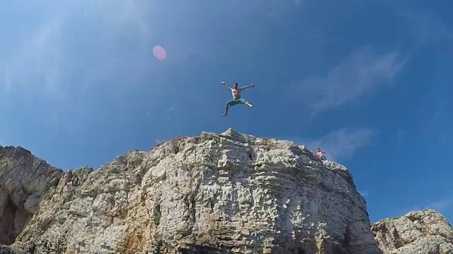 水下慢镜头:欢快的男子双手从海洋悬崖上跳下来视频下载