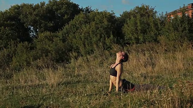 日落时分，运动女性在公园里做阿斯汤加瑜伽视频下载
