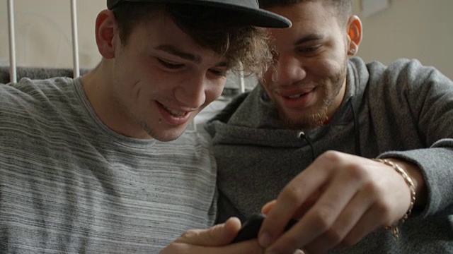 两名男生在卧室查看手机短信视频下载