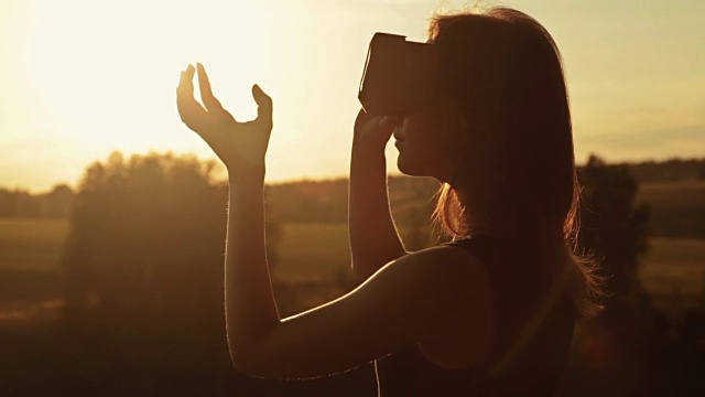 日落时分，一名女子在森林中佩戴虚拟现实眼镜视频素材