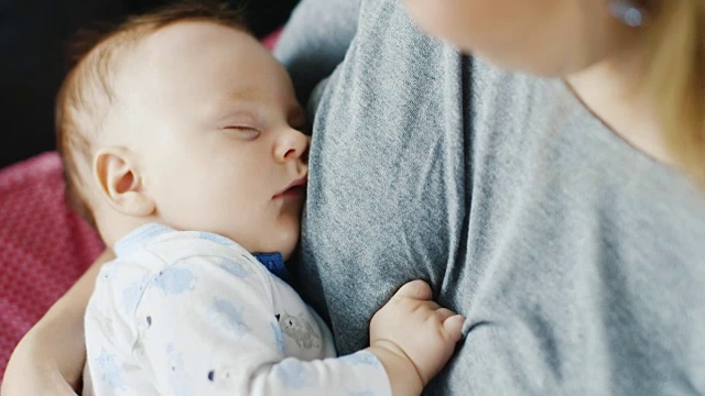 两个月大的孩子睡在妈妈的胸口。母亲抱着儿子视频素材