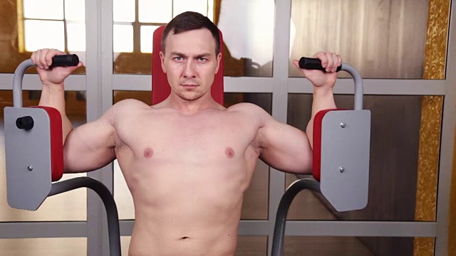 蝴蝶健身器-年轻的健美者在健身房做胸部的重量锻炼视频下载