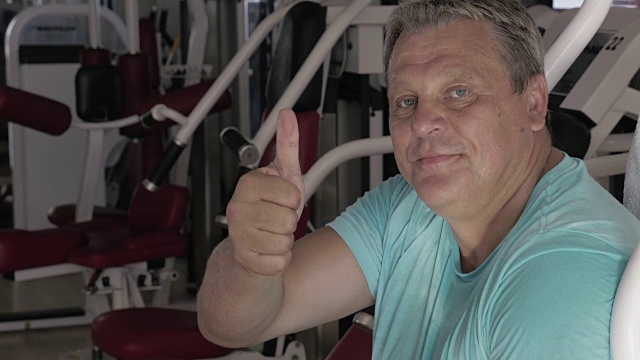 老男人在健身房锻炼的时候翘着大拇指微笑着视频下载