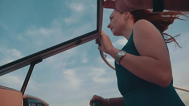 男人帮助红发女孩穿着绿松石衣服驾驶摩托艇。浪漫的约会视频下载