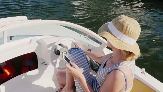 一名女子戴着帽子在一艘船上漂着，用的是手机。从以上观点。概念:在欧洲的西班牙海上度假视频下载