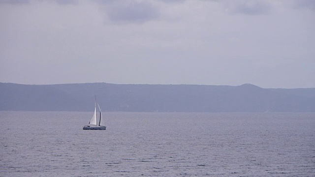 帆船在多云的天气中航行，背景是美丽的海景。不认识的人的剪影。视频素材
